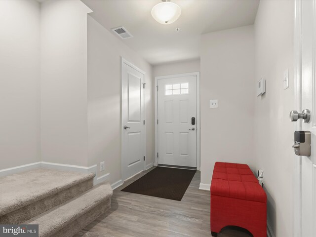 entrance foyer featuring wood finished floors, baseboards, and stairway