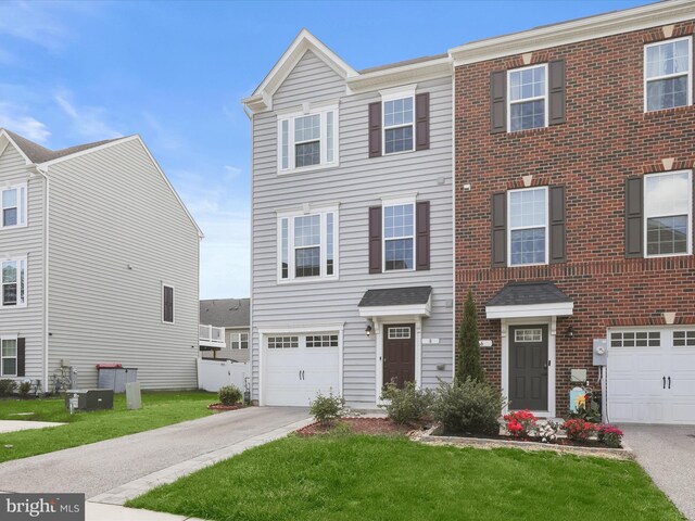 view of property with an attached garage, concrete driveway, and a front lawn