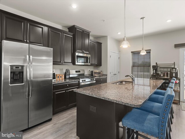 kitchen featuring stainless steel appliances, a sink, light wood-type flooring, an island with sink, and recessed lighting