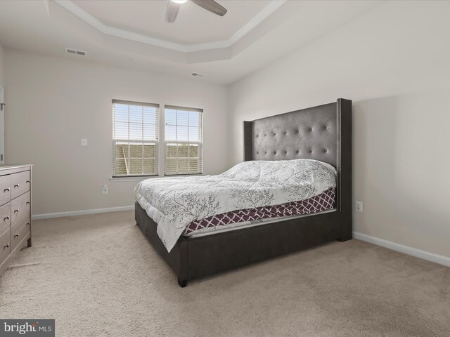 bedroom with a tray ceiling, light carpet, ornamental molding, baseboards, and a ceiling fan