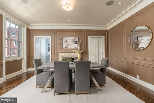 dining area featuring crown molding, baseboards, dark wood finished floors, and a decorative wall