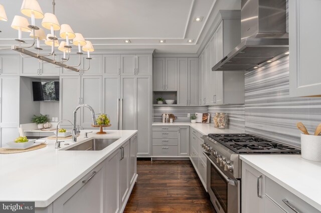 kitchen with wall chimney range hood, stainless steel range, a notable chandelier, a sink, and recessed lighting