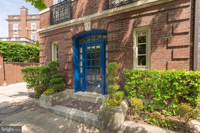 view of exterior entry featuring brick siding and a balcony