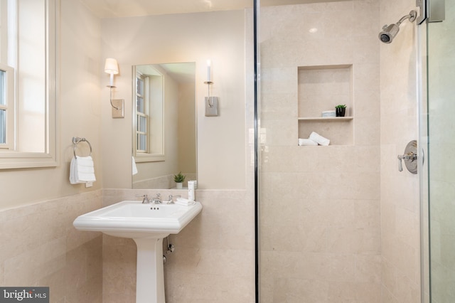 bathroom with tile walls, a wainscoted wall, and a shower stall