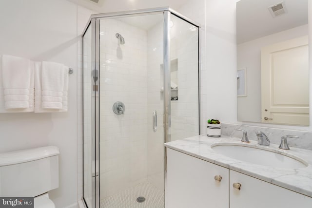bathroom with vanity, a stall shower, toilet, and visible vents