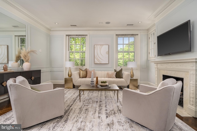 living area with a healthy amount of sunlight, ornamental molding, wood finished floors, and visible vents