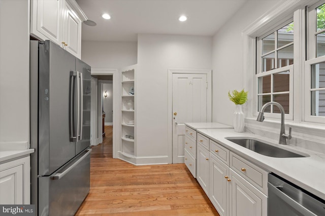 6763 25th St N, Arlington, VA 22213 - kitchen with appliances with stainless steel finishes, a sink, white cabinetry, light countertops, and light wood-style flooring