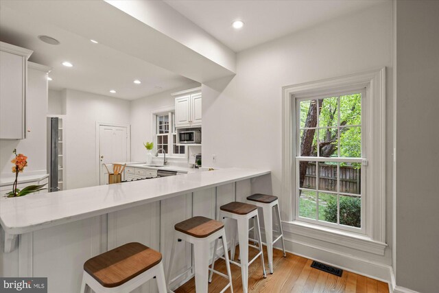 6763 25th St N, Arlington, VA 22213 - kitchen with stainless steel microwave, a sink, light countertops, light wood-type flooring, and healthy amount of natural light