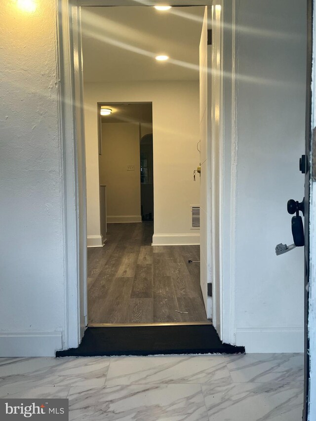 hallway featuring visible vents, arched walkways, marble finish floor, and baseboards