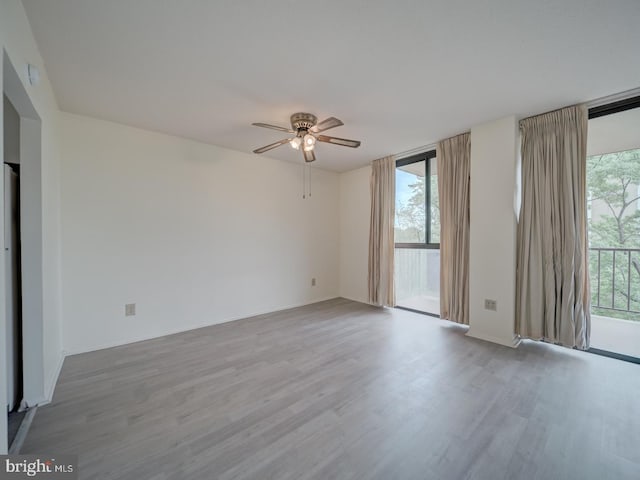 spare room with ceiling fan, floor to ceiling windows, and wood finished floors