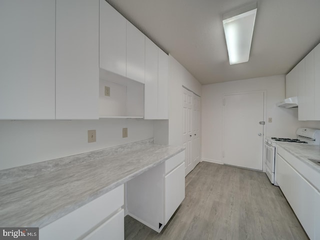 kitchen with white gas range, light countertops, light wood-style floors, under cabinet range hood, and white cabinetry