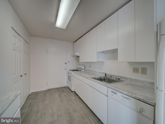 kitchen featuring light wood-type flooring, a sink, light countertops, under cabinet range hood, and white appliances