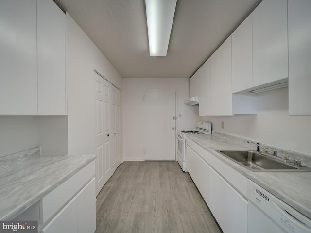 kitchen featuring white appliances, white cabinetry, under cabinet range hood, a sink, and light wood-style flooring