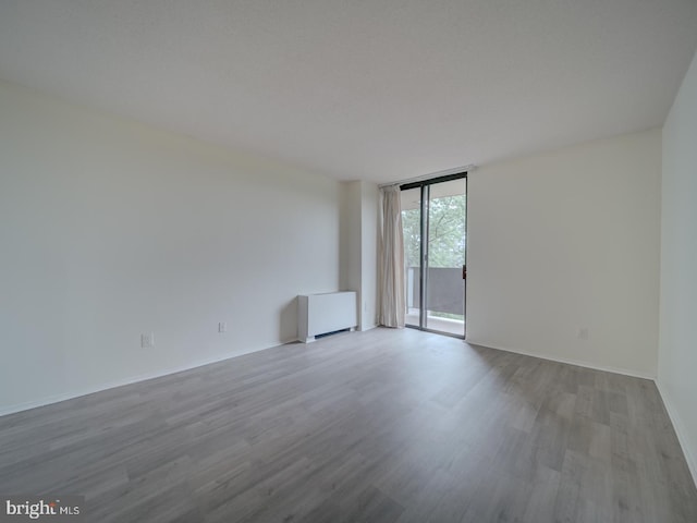 empty room featuring expansive windows, baseboards, and wood finished floors