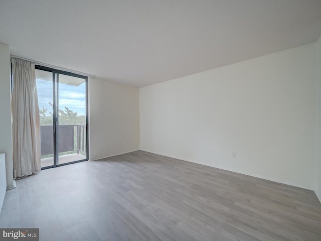 spare room featuring expansive windows and wood finished floors