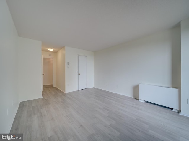 spare room featuring baseboards and light wood finished floors