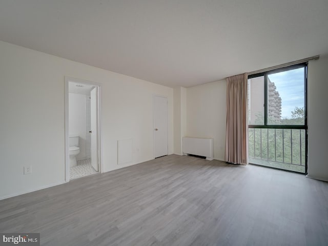unfurnished room featuring radiator heating unit, floor to ceiling windows, and wood finished floors