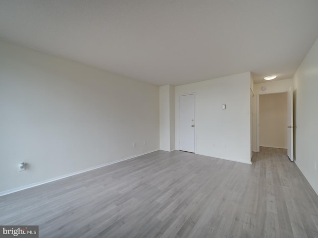 spare room with baseboards and wood finished floors