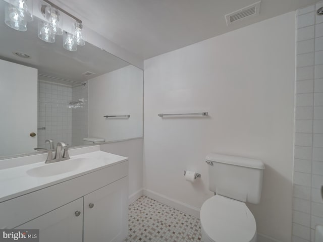 bathroom with vanity, toilet, baseboards, visible vents, and tiled shower