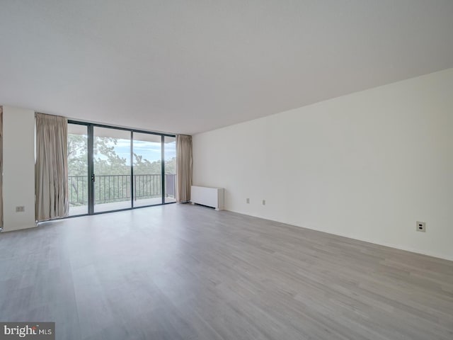 empty room with a wall of windows and wood finished floors