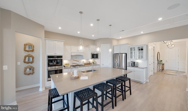 33833 Joel Ln, Lewes, DE 19958 - kitchen featuring a breakfast bar area, a large island with sink, light wood finished floors, stainless steel appliances, and white cabinetry