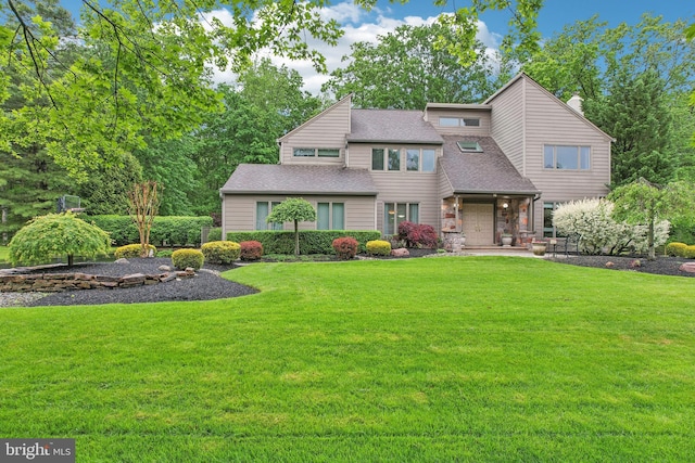 mid-century home with a front yard, a shingled roof, and a chimney