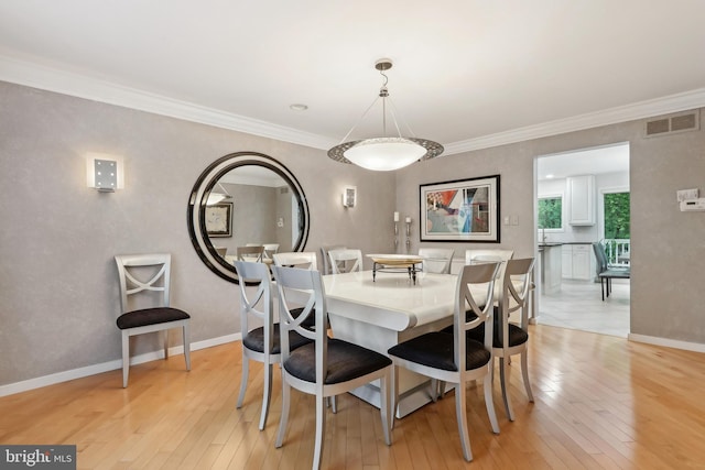 dining room featuring light wood-style floors, baseboards, and ornamental molding