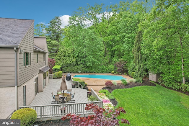 outdoor pool featuring outdoor dining space, a deck, and a lawn