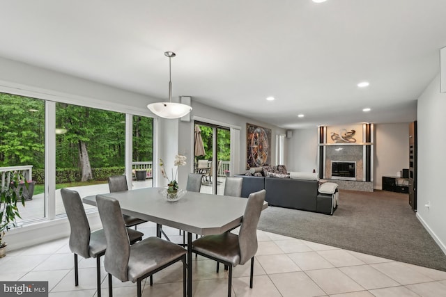 dining area featuring light colored carpet, recessed lighting, a glass covered fireplace, light tile patterned floors, and baseboards