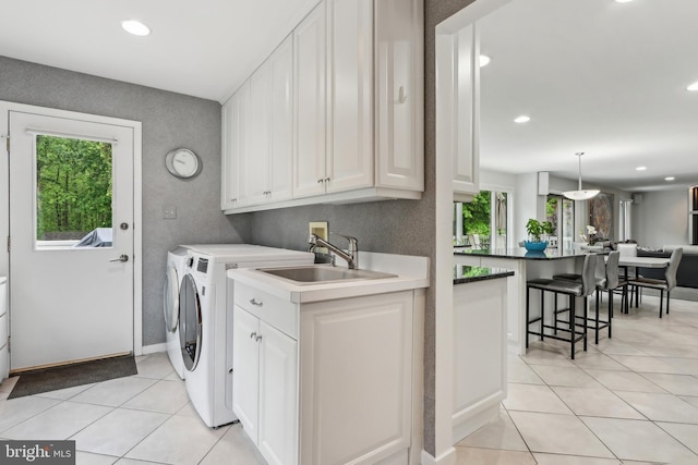 clothes washing area with washer and dryer, light tile patterned floors, recessed lighting, baseboards, and cabinet space