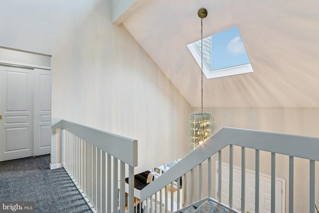 stairs with a skylight, a chandelier, carpet, and lofted ceiling