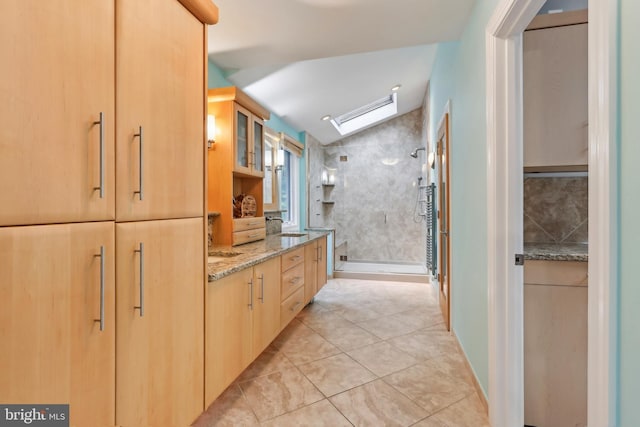 full bath with a stall shower, vaulted ceiling, tile patterned flooring, vanity, and decorative backsplash