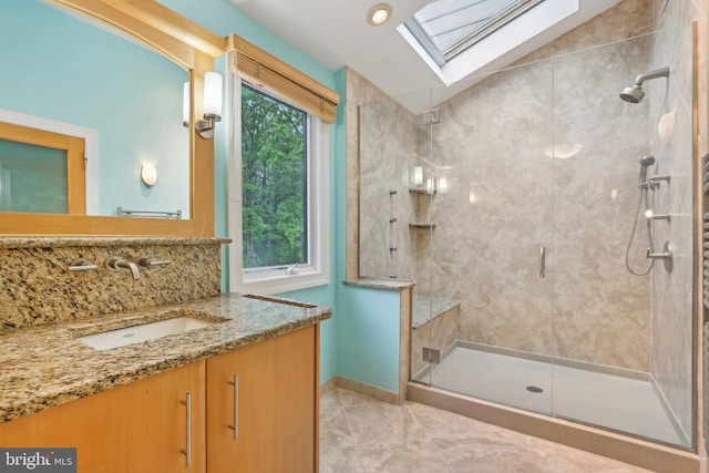 full bath featuring a skylight, a shower stall, baseboards, and vanity