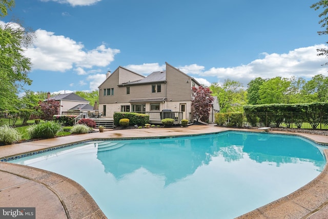 view of swimming pool with a deck, fence, and a diving board