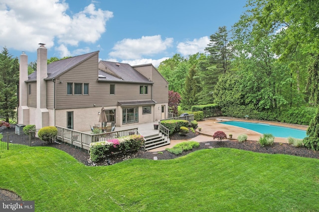 rear view of house with a deck, a chimney, and an outdoor pool