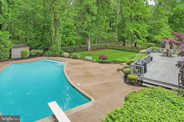 view of pool with a wooden deck, outdoor dining space, a diving board, and an outdoor structure