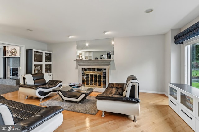living room with a glass covered fireplace, wood finished floors, baseboards, and recessed lighting