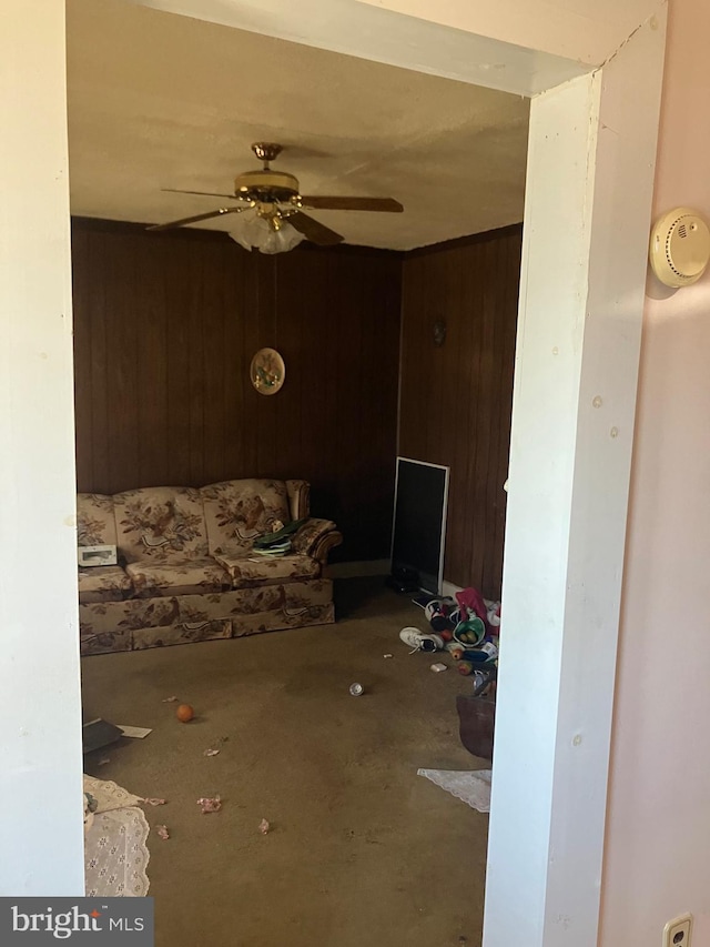 unfurnished living room with ceiling fan and wood walls