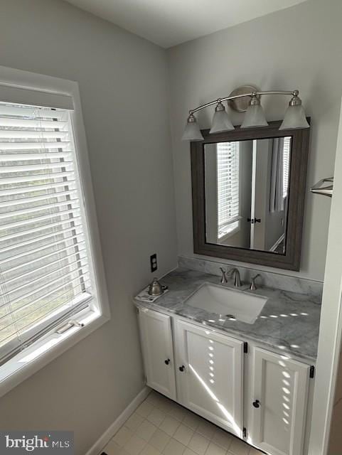 bathroom with vanity, baseboards, tile patterned flooring, and a wealth of natural light