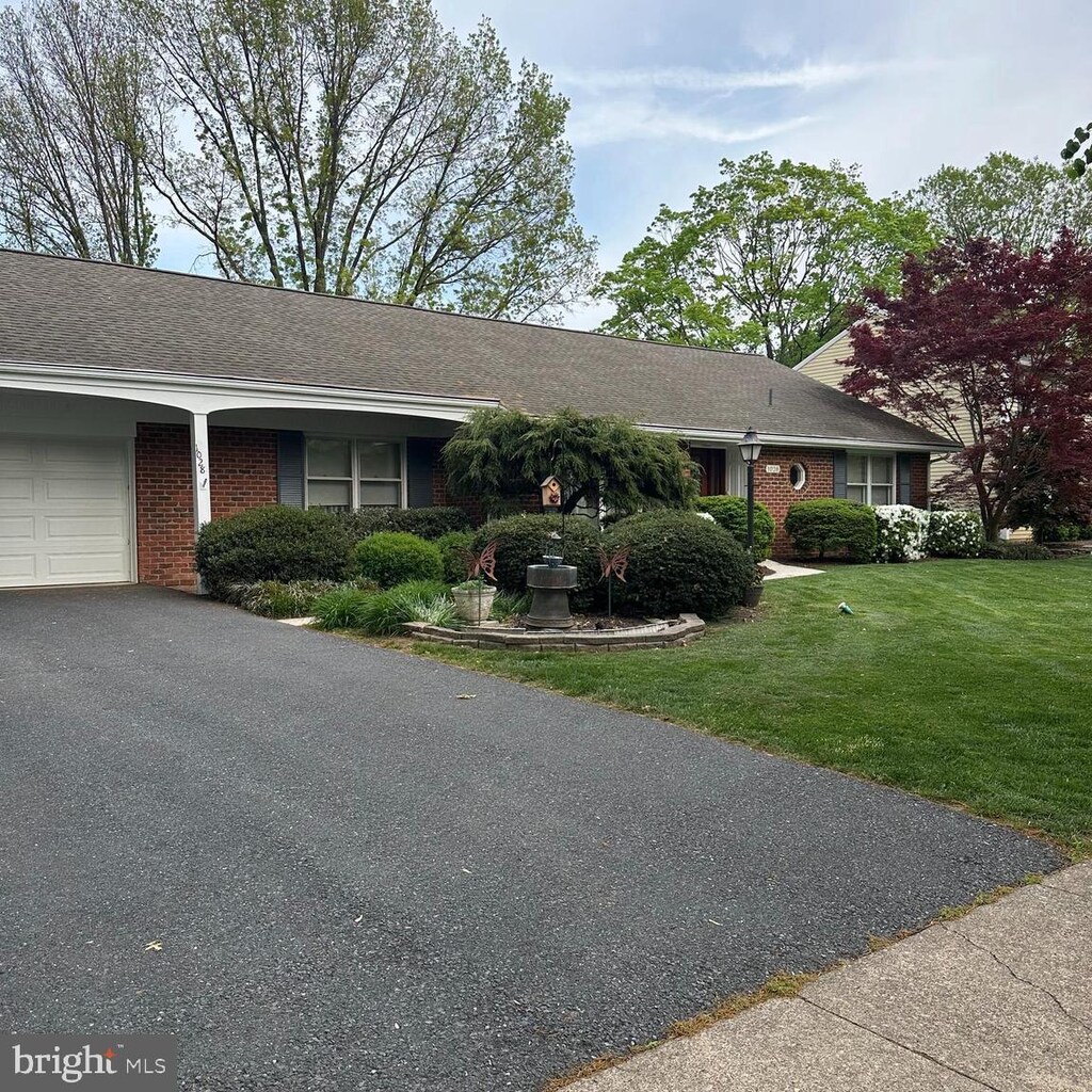 single story home with brick siding, an attached garage, driveway, and a front yard