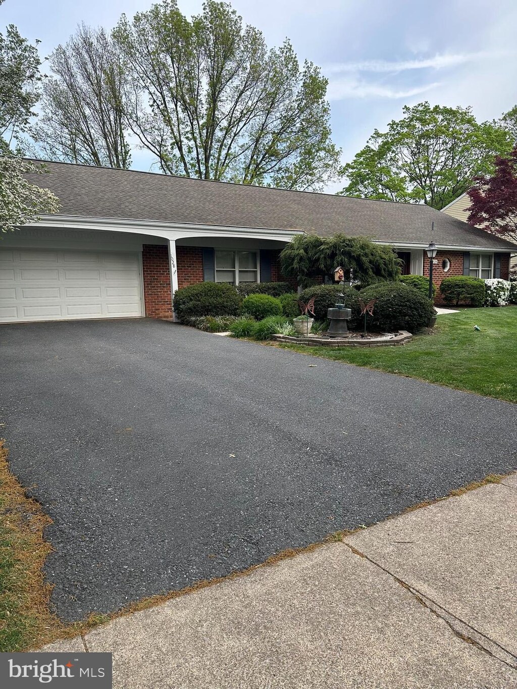 ranch-style home featuring an attached garage, a front yard, driveway, and brick siding