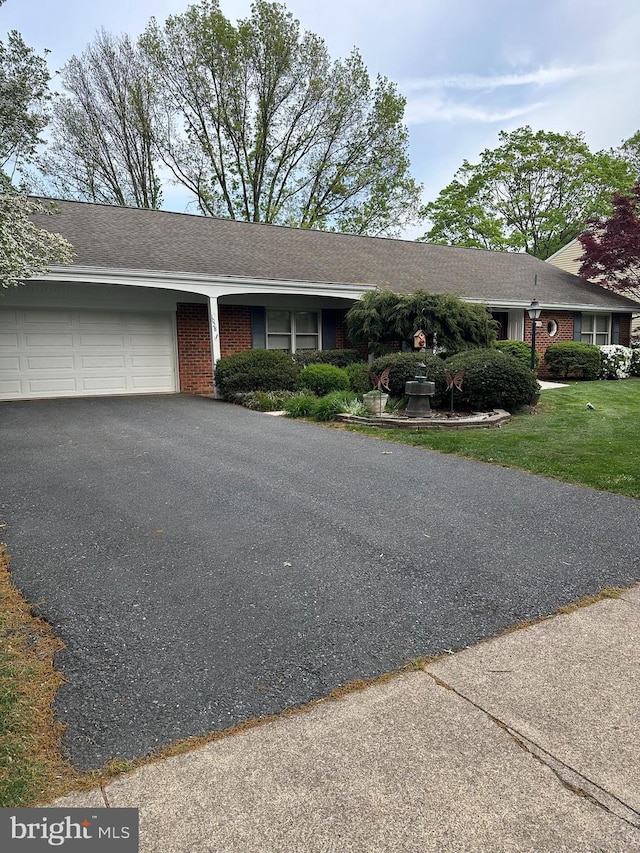 ranch-style home featuring an attached garage, a front yard, driveway, and brick siding