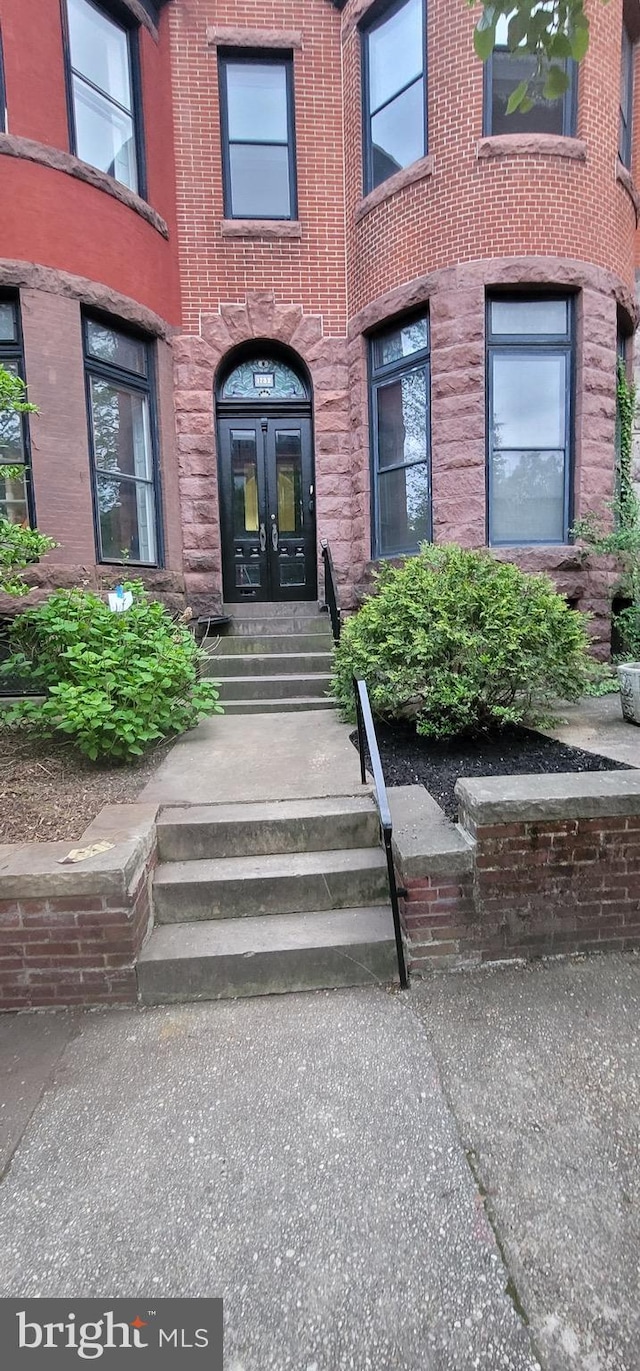 view of exterior entry featuring french doors and brick siding
