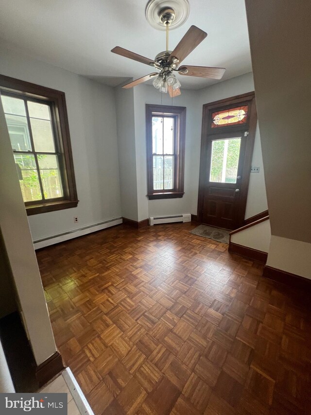 unfurnished room with a baseboard heating unit, ceiling fan, and baseboards