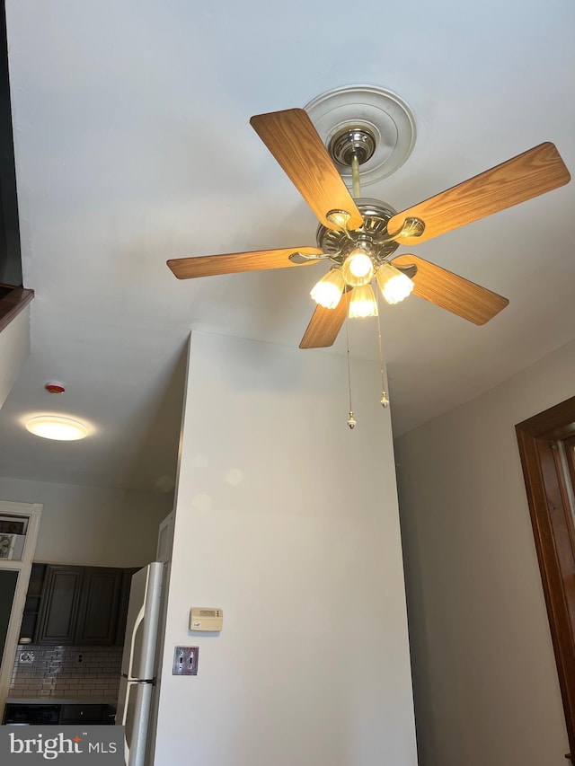 kitchen view of freestanding refrigerator, ceiling fan, and tasteful backsplash
