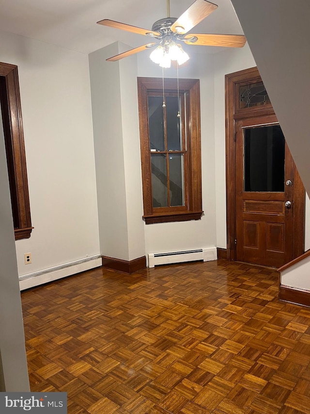 unfurnished living room with a baseboard heating unit, a ceiling fan, and baseboards