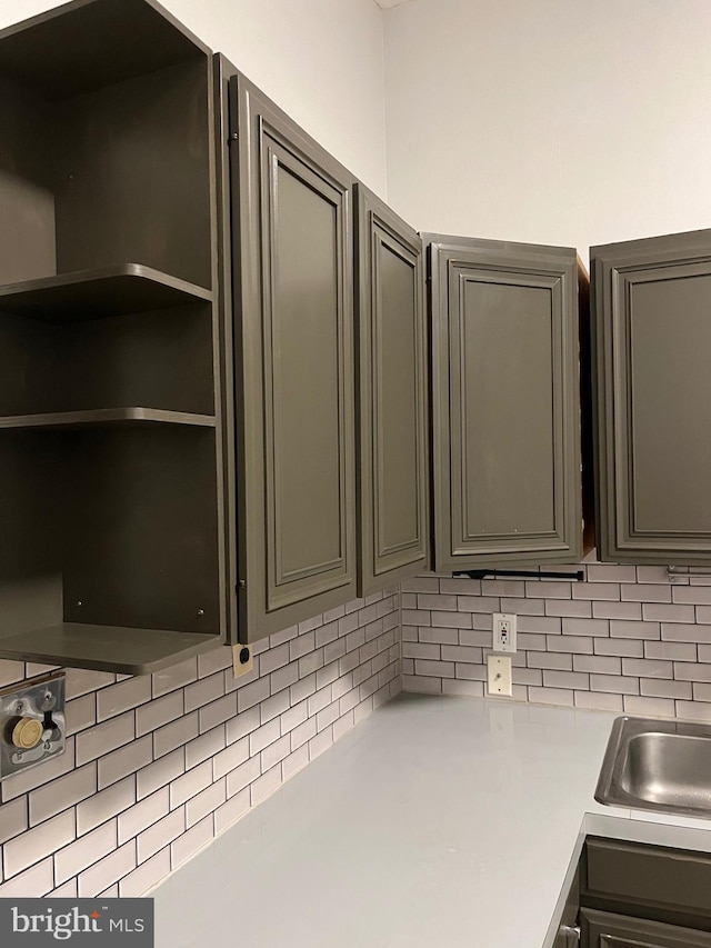 kitchen featuring light countertops, open shelves, backsplash, and gray cabinetry