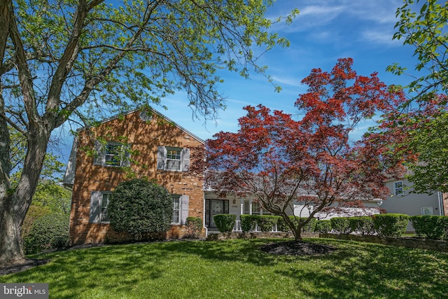 view of front facade with brick siding and a front lawn