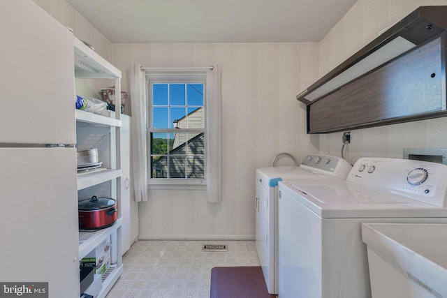washroom featuring laundry area, baseboards, light floors, a sink, and independent washer and dryer
