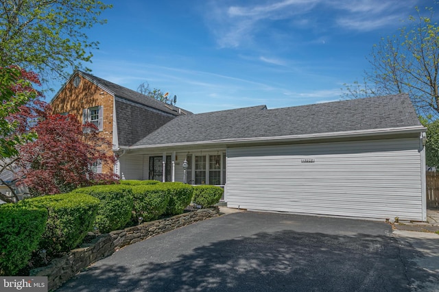 view of front of house with a garage, roof with shingles, and aphalt driveway